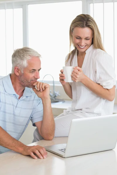 Casal alegre usando laptop juntos no balcão — Fotografia de Stock