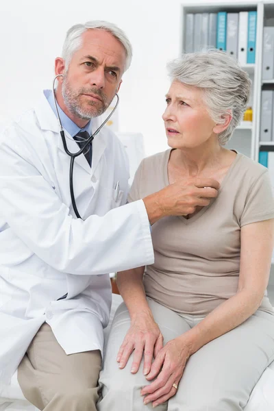 Médico revisando pacientes latidos del corazón usando estetoscopio —  Fotos de Stock