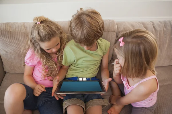 Three kids using digital tablet in living room — Stock Photo, Image