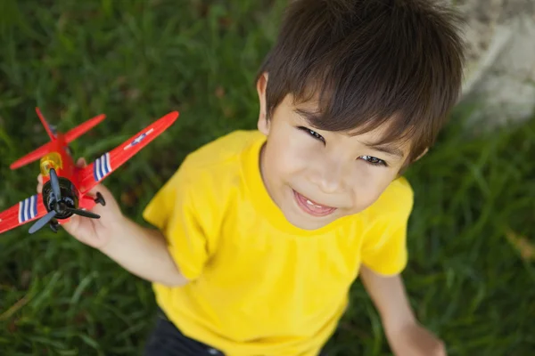 Young boy playing with a toy plane at park — Stock Photo, Image