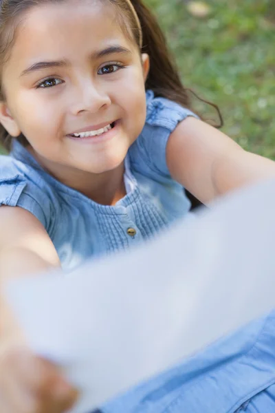 Sorrindo menina segurando um papel desfocado no parque — Fotografia de Stock