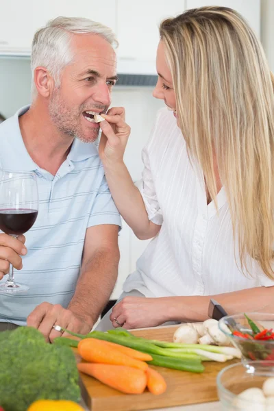 Affectionate couple preparing dinner together and drinking red wine — Stock Photo, Image