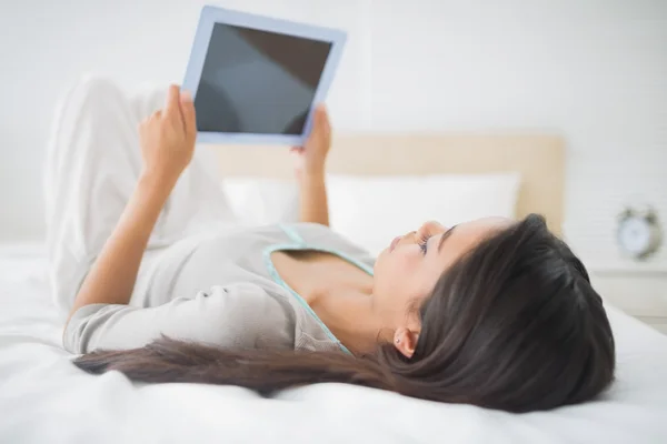 Chica acostada en la cama mirando a su PC tableta —  Fotos de Stock