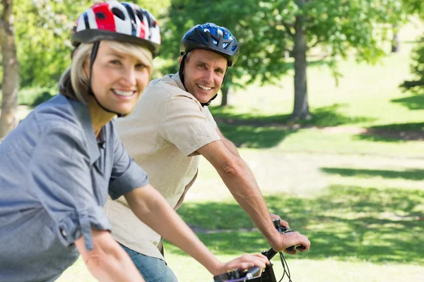 Happy couple riding bicycles in park — Stock Photo, Image