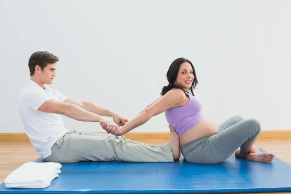 Masseur stretching pregnant womans arms and shoulders — Stock Photo, Image