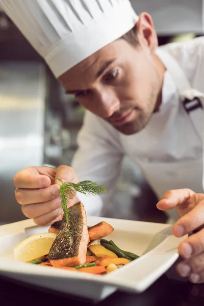 Gros plan d'un chef masculin concentré garnissant la nourriture — Photo