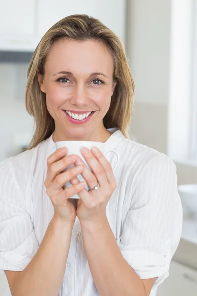 Lachende vrouw zitten en houden mok — Stockfoto