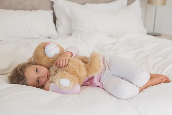 Menina com brinquedo de pelúcia descansando na cama — Fotografia de Stock