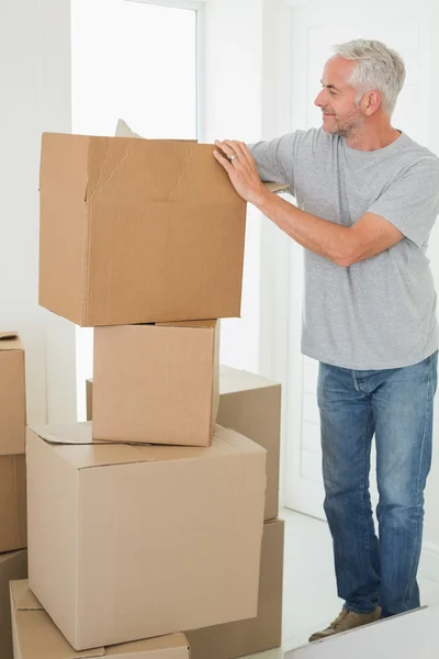 Hombre sonriente mirando cajas móviles de cartón —  Fotos de Stock