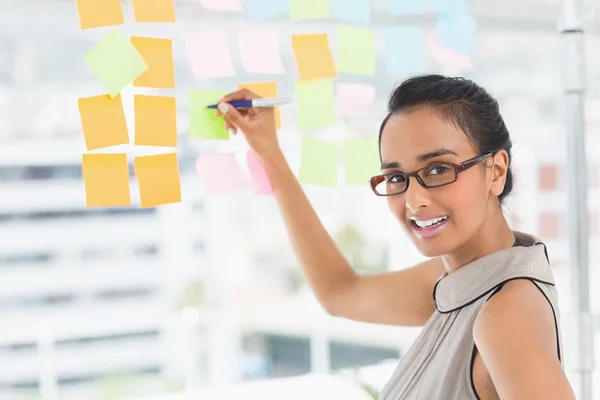 Designer writing on sticky notes on window — Stock Photo, Image