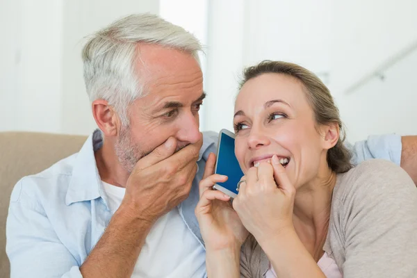 Szczęśliwa para słuchania telefon razem na kanapie — Zdjęcie stockowe
