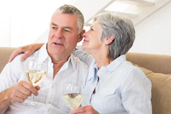 Äldre par sitter på soffan dricka vitt vin — Stockfoto