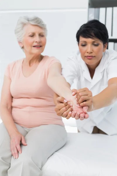 Female physiotherapist examining a senior patients hand — Stock Photo, Image