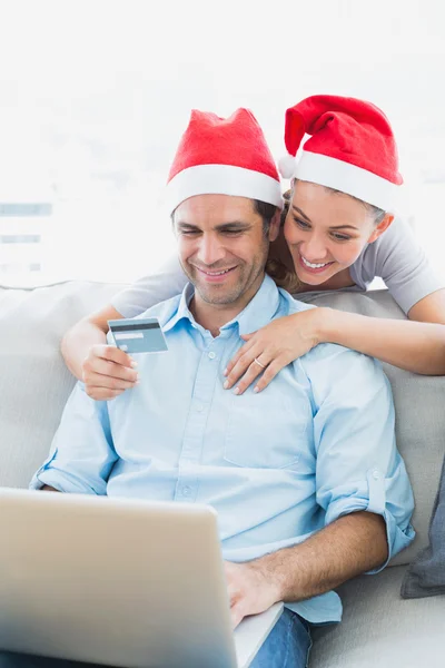 Roztomilý pár v santa klobouky nakupování online s notebookem Royaltyfria Stockfoton