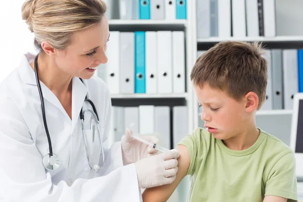 Boy receiving an injection by doctor Stock Image