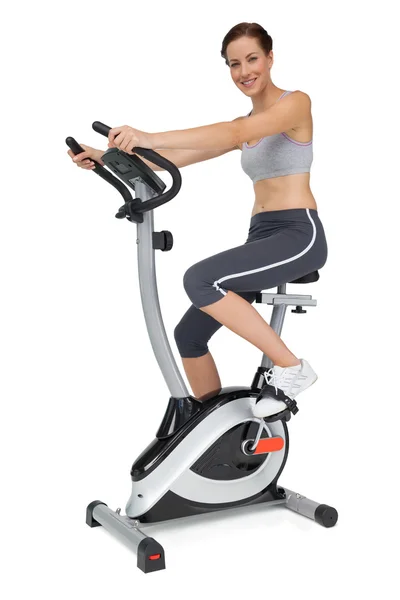 Beautiful young woman on stationary bike — Stock Photo, Image