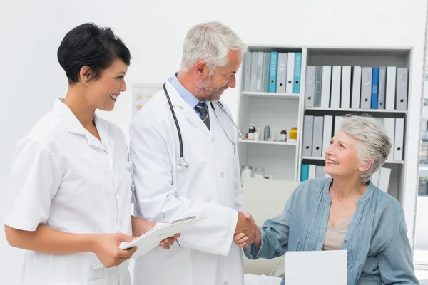 Smiling female patient and doctor shaking hands — Stock Photo, Image