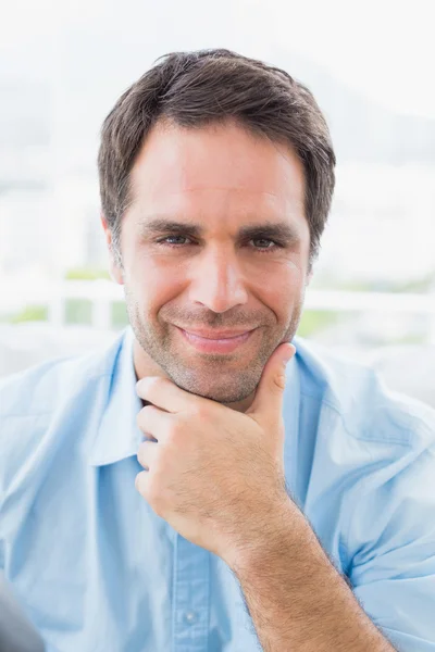 Thinking handsome man sitting on the couch looking at camera — Stock Photo, Image