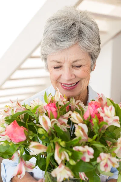 Gepensioneerde vrouw holding boeket van bloemen en glimlachen — Stockfoto