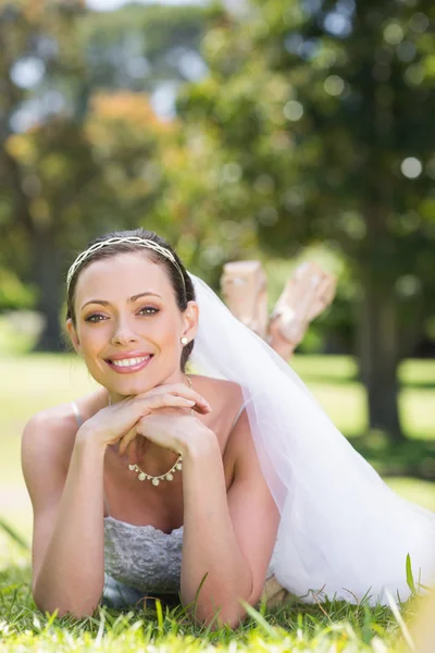 Bride lying on grass in park — Stock Photo, Image