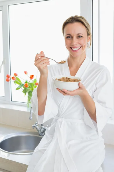 Smiling woman in bathrobe having cereal — Stock Photo, Image