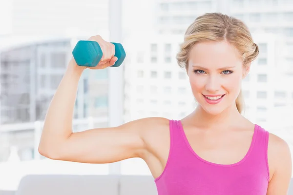 Happy blonde lifting dumbbell and flexing — Stock Photo, Image