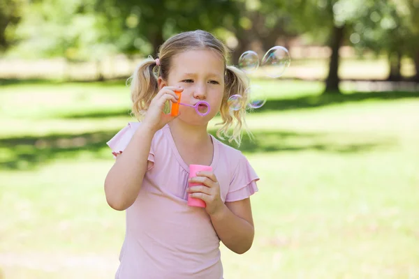 Dziewczyna dmuchanie baniek mydlanych w parku — Zdjęcie stockowe