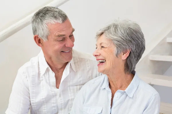 Casal de idosos sentados nas escadas sorrindo um para o outro — Fotografia de Stock