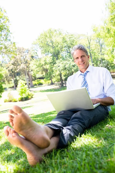 Affärsman med laptop sitter i parken — Stockfoto