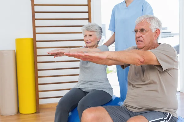 Terapeut hjälpa äldre par med övningar — Stockfoto