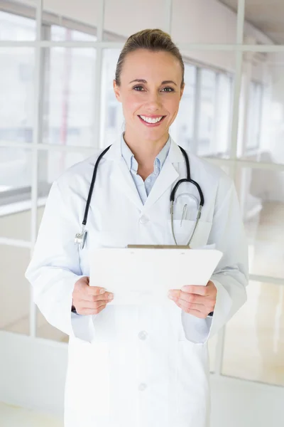 Happy beautiful female doctor with clipboard in hospital — Stock Photo, Image