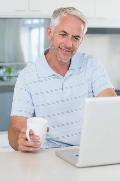 Случайный человек использует свой ноутбук, когда пьет кофе — стоковое фото