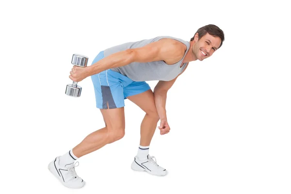 Smiling fit young man exercising with dumbbell — Stock Photo, Image
