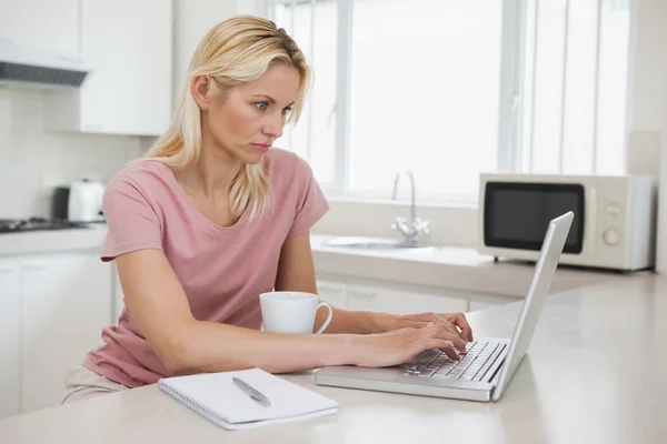 Seriös kvinna med laptop i köket — Stockfoto