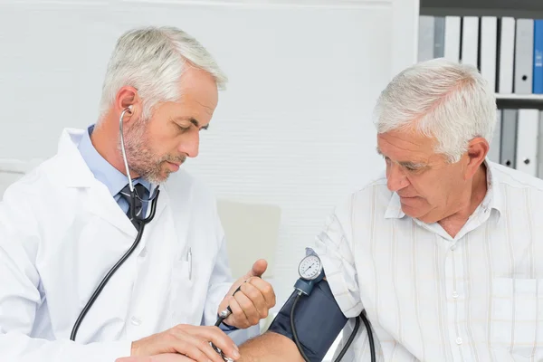 Doctor taking the blood pressure of his retired patient — Stock Photo, Image