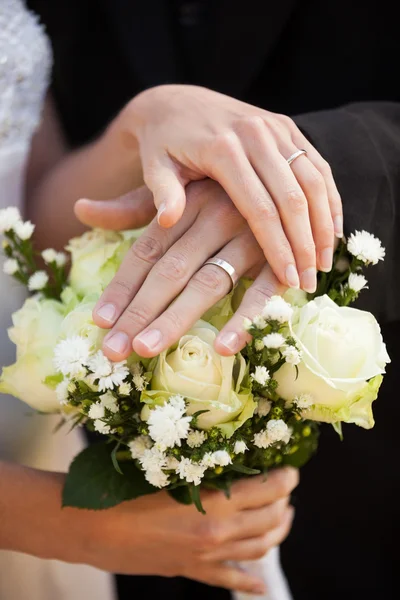 Jonggehuwde paar met bruiloft ringen en boeket — Stockfoto