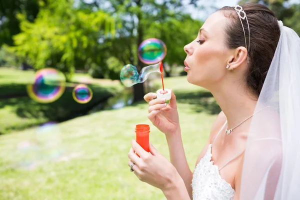 Bride blowing bubbles in garden — Stock Photo, Image