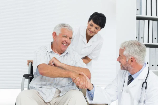 Счастливый пожилой пациент и доктор пожимают руку — стоковое фото