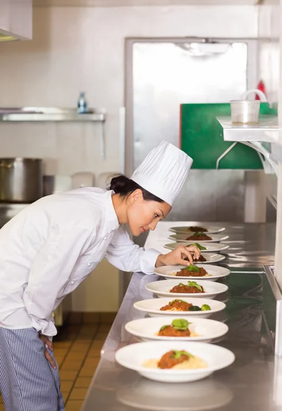 Chef feminino concentrado guarnição de alimentos na cozinha — Fotografia de Stock