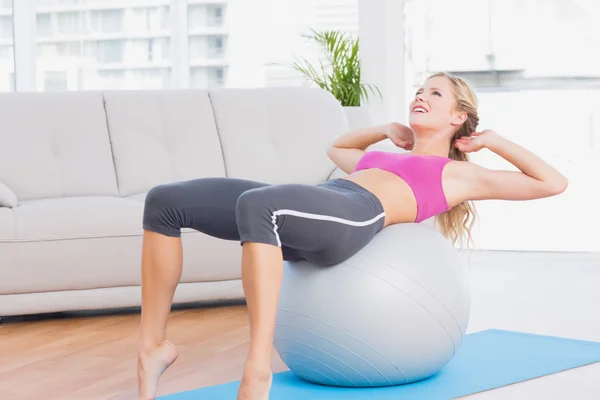 Blondin gör sit ups med övning boll — Stockfoto