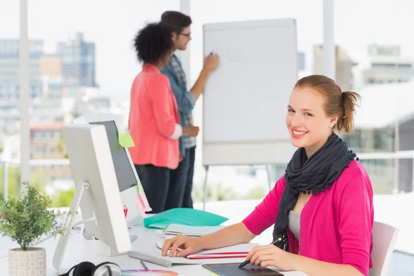 Artista femminile utilizzando tablet grafico con colleghi in ufficio — Foto Stock