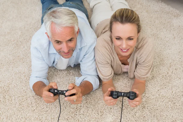 Sorrindo casal deitado no tapete jogando videogames — Fotografia de Stock