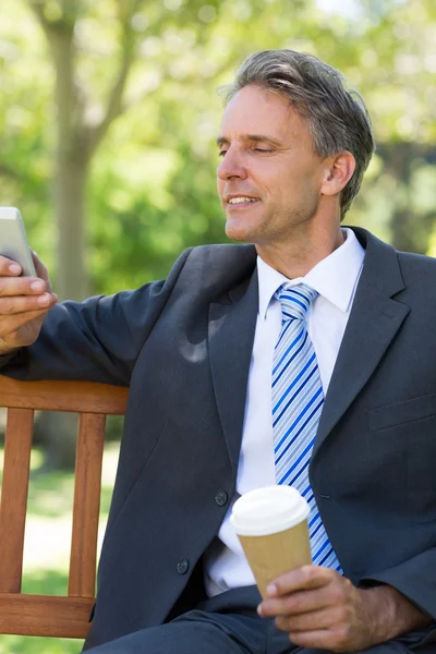 Бизнесмен, использующий мобильный телефон в парке — стоковое фото