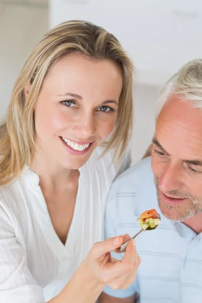 Femme heureuse nourrissant son partenaire d'une cuillère de légumes — Photo