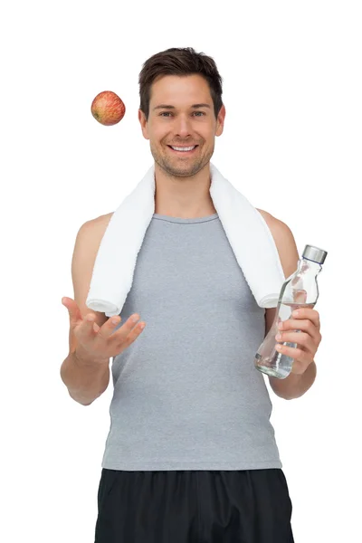 Smiling fit young man with apple and water bottle — Stock Photo, Image