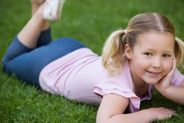 Smiling relaxed girl lying on grass at park — Stock Photo, Image