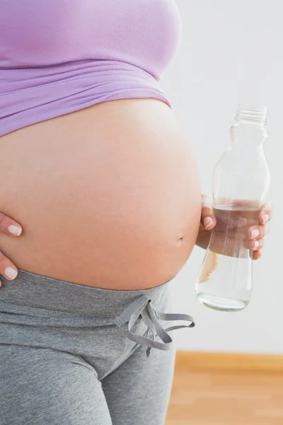 Těhotná žena drží láhev vody — Stock fotografie