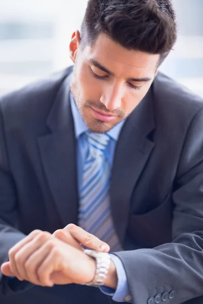 Businessman sitting checking his watch — Stock Photo, Image