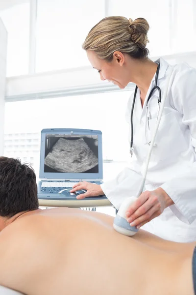 Medico che utilizza l'ecografia sul retro del paziente maschile — Foto Stock