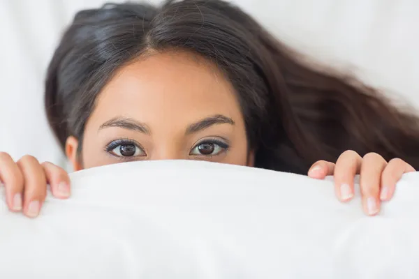 Mädchen guckt unter der Bettdecke hervor — Stockfoto